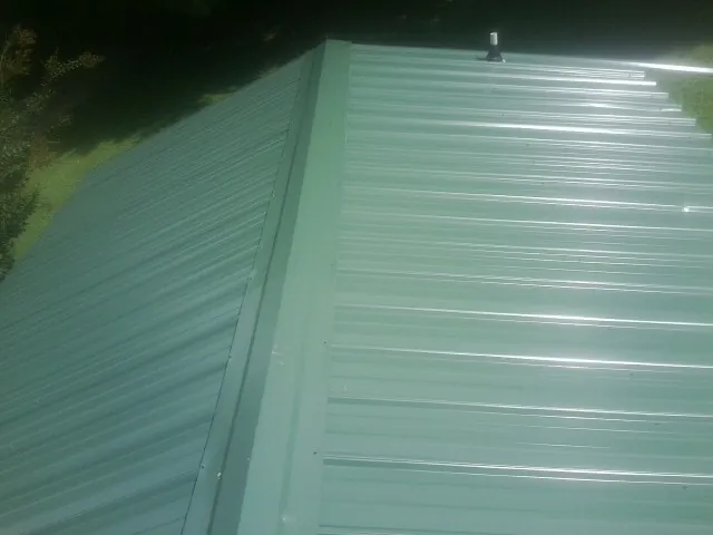 New green metal panels meeting at the ridge of a roof — Flat Roof Repair work by our crew in Astatula