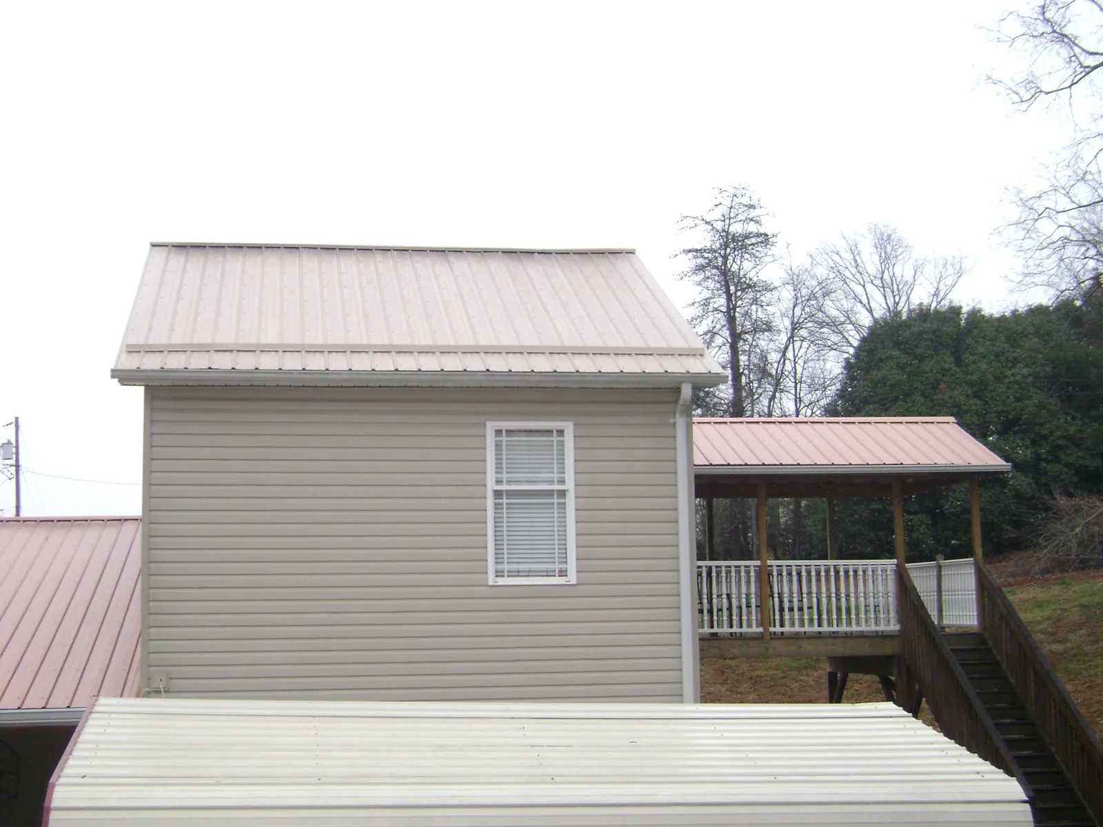 Tan metal roofs on a two story addition and attached porch, from a Roof Replacement job in Astatula